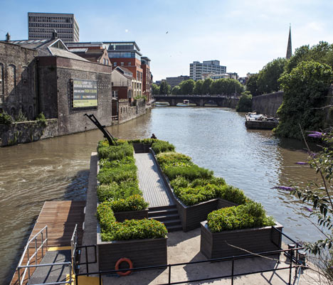 Picture of planters of greenery surrounded by canal with warehouse in the distance