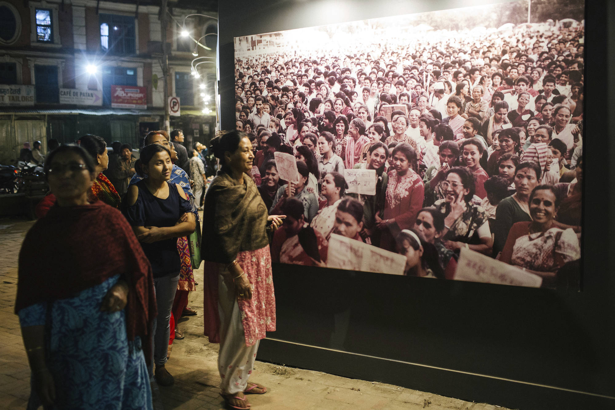 Indian woman standing in front of a giant photo of other women