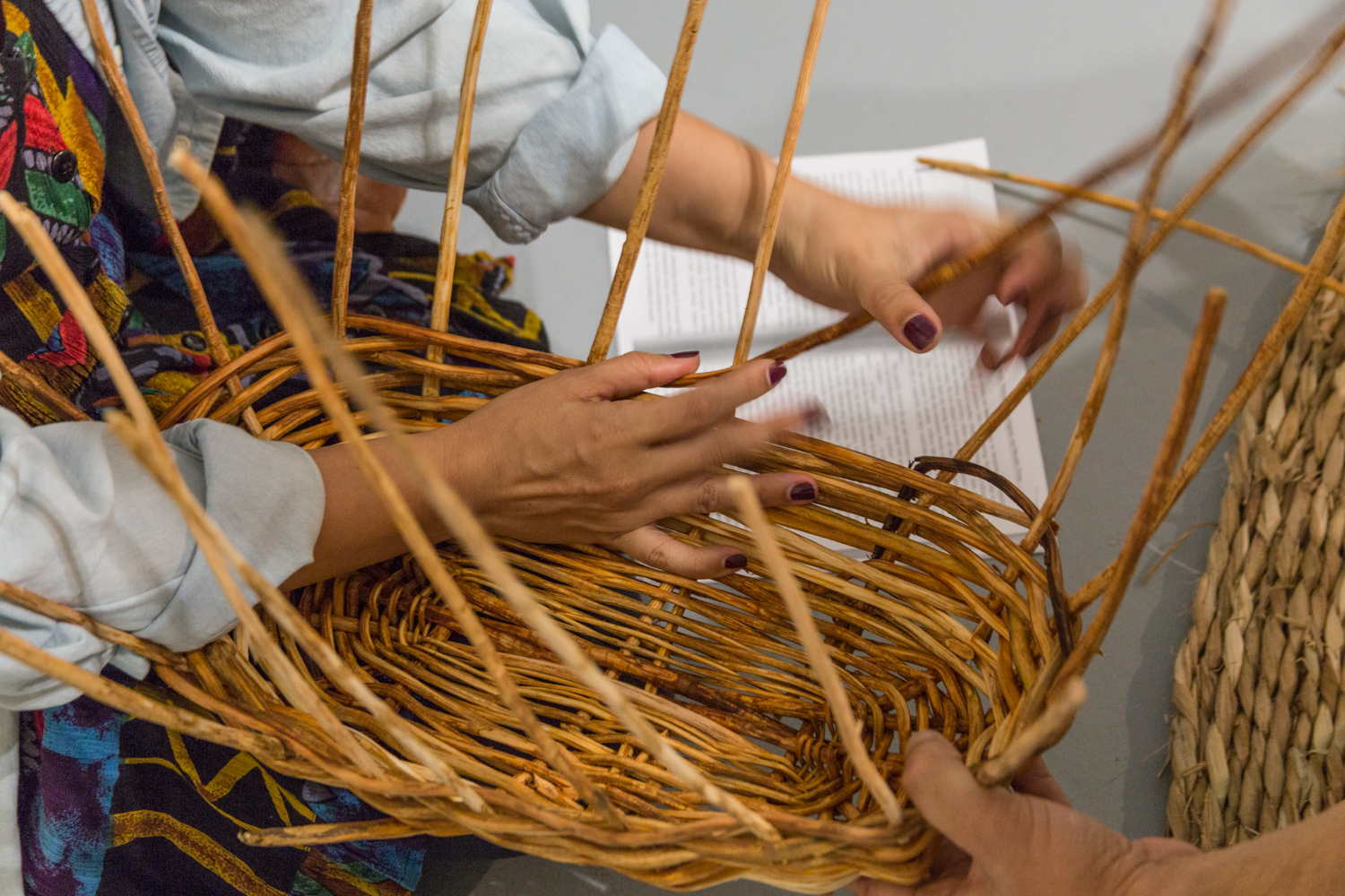 Hands weaving a basket together