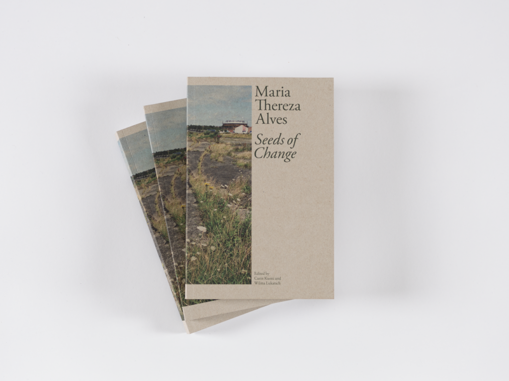 Maria Thereza Alves: Seeds of Change. Edited by Carin Kuoni and Wilma Lukatch. Published by Amherst College Press and the Vera List Center for Art and Politics, The New School, 2023. Designed by Common Name. 216 pages. Photograph by Re'al Christian, courtesy the Vera List Center. Three copies of Seeds of Change stacked and fanned out with front cover visible. Front cover features an image from Seeds of Change: Liverpool, 2004, wraps around front and back cover. Dark green text on a light brown background reads: Maria Thereza Alves Seeds of Change Edited by Carin Kuoni and Wilma Lukatsch